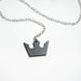 Close up of the metal crown pendant hanging from a chain on the Oblivion Keyblade